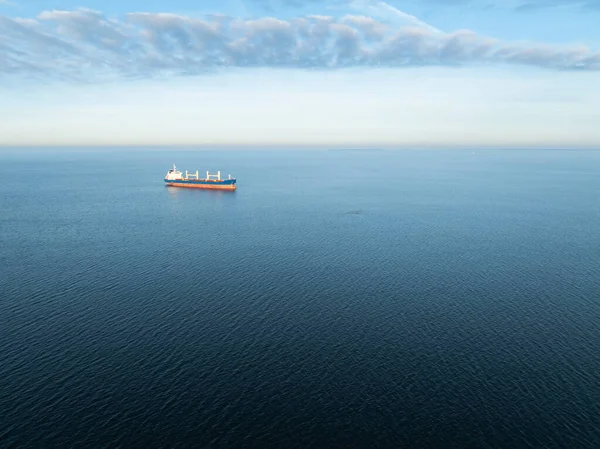 Geniş mavi Baltık Denizi 'ni açık bir gökyüzünün altında geçen büyük bir kargo gemisinin uzaktan kumandalı hava aracı görüntüsü..