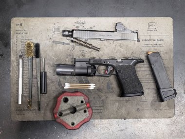 27 Ocak 2026. Baltık Eyaletleri Yüksek açılı Glock 19 Gen5 tabancasının teknik temizlik minderinde profesyonel bakım ve geliştirme araçları ile bir atölyede.