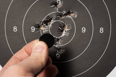 Bir Erkek El 'in Yakın plan Çekimi Mesafe' deki bir Kağıtlı Atış Hedefine Siyah Hedef Noktası yerleştiriyor.