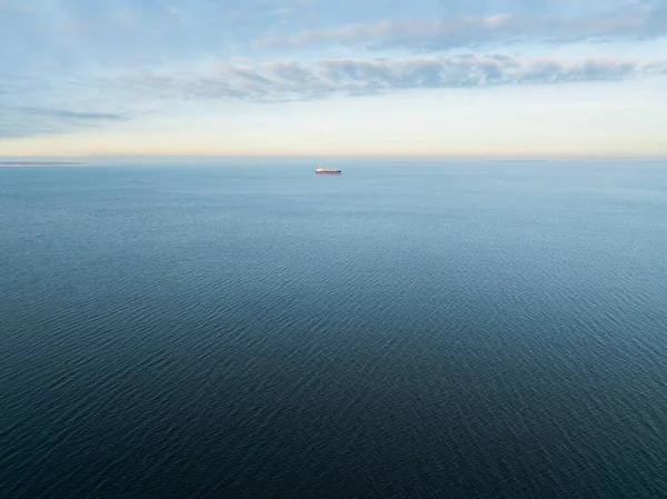 Sakin mavi Baltık Denizi 'nde sabah gökyüzünün altında giden büyük bir kargo gemisinin geniş açılı görüntüsü..