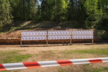 ESTONIA - 19 Mayıs 2023: Tahta tezgahlar ve kütükler üzerinde kağıt hedefler olan bir ormanda atış poligonu.