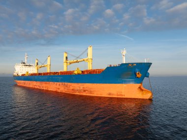 Gün batımında mavi Baltık Denizi 'nden geçen büyük bir yük gemisinin yüksek açılı insansız hava aracı görüntüsü..