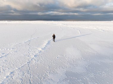 Finlandiya 'da kar beyazı ile kaplı donmuş Baltık Denizi' nde yalnız bir insanın yüksek açılı hava aracı görüntüsü.