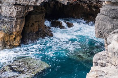 Güçlü okyanus dalgaları Cascais Portekiz 'deki kayalık kayalıkların altında karanlık deniz mağarasına çarpıyor. Güzel turkuaz su ve beyaz köpük..