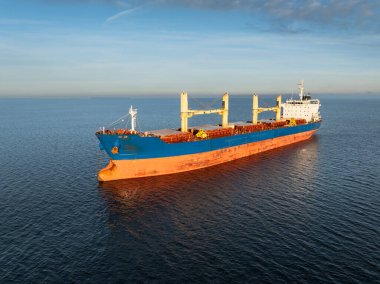 Estonya yakınlarındaki sakin Baltık Denizi 'ne demirlemiş büyük mavi ve turuncu bir kargo gemisinin insansız hava aracı görüntüsü..