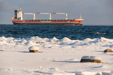 Büyük paslı kargo gemisi kış günü karlı Estonya kıyıları yakınlarında Baltık Denizi 'nin mavi sularında yelken açıyor..
