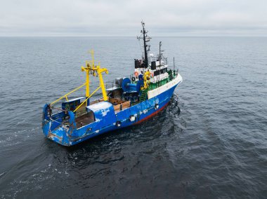 Baltık Denizi Estonya 'sının açık sularında yüzen mavi ticari balıkçı teknesinin insansız hava aracı görüntüsü..