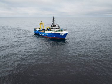 Mavi endüstriyel balıkçı teknesinin hava aracı görüntüsü Baltık Denizi 'nin soğuk sularında bir ağı sürüklüyor..