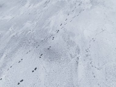 Kışın Baltık Denizi 'nin donmuş yüzeyi boyunca uzanan insan ayak izlerinin tepeden tırnağa görüntüsü..