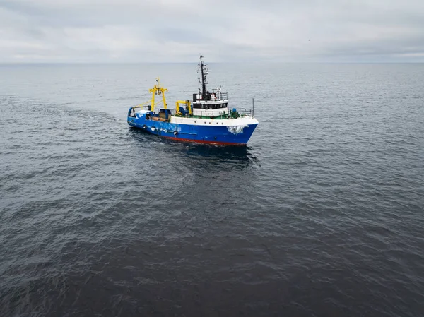 Mavi endüstriyel balıkçı teknesinin hava aracı görüntüsü Baltık Denizi 'nin soğuk sularında bir ağı sürüklüyor..