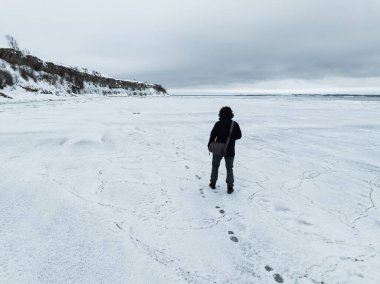 Estonya 'daki Pakistan Yarımadası kayalıkları yakınlarındaki donmuş Baltık Denizi yüzeyinde yürüyen yalnız bir yolcunun hava görüntüsü..