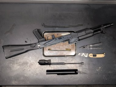 Temizlik aletleri, çoklu aletler ve bıçak ile profesyonel bakım ve periyodik teknik servis için bir tezgahta parçalanmış modern saldırı tüfeği.