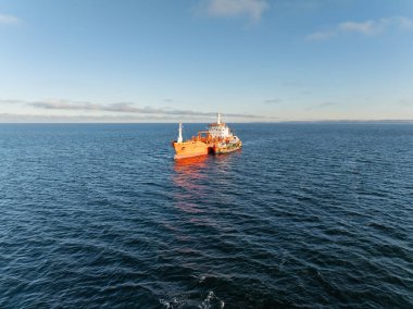 Baltık Denizi 'nin mavi sularında turuncu yakıt tankeri yakıt ikmal gemisiyle gemi sığınağı operasyonunu gösteren hava aracı görüntüsü. .