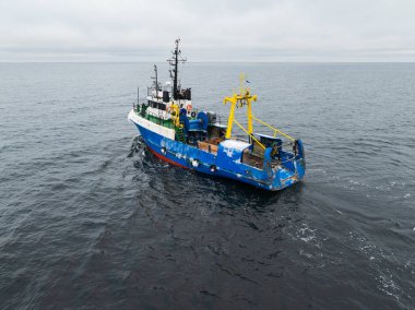 Sonbahar boyunca Baltık Denizi 'nin sakin gri sularında ilerleyen mavi sanayi balıkçı teknesinin insansız hava aracı görüntüsü..