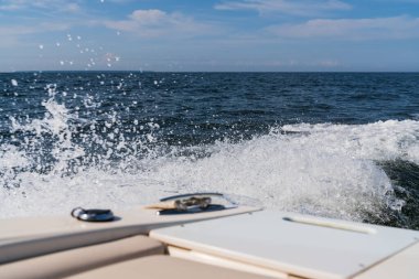 Güneşli bir yaz gününde mavi Baltık Denizi 'nde seyreden hızlı bir motordan beyaz su ve köpük sıçrıyor..