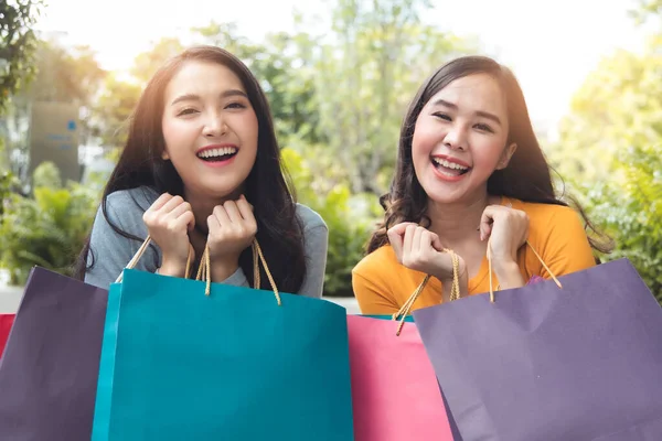 Asain woman in shopping. Happy woman with shopping bags enjoying in shopping.lifestyle concept.Smiling girl  holding colour paper bag.Friends walking in shopping mall