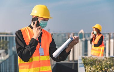 Mekanik fabrika okuma talimatları mühendisleri gülümseyen imalatçı kadın ve erkek, beyaz gökyüzü ve bina kulesinin arka planına güvenerek ayakta duruyorlar. Sanatsal geçmişi parlak insanları yetiştirme sanayisi.