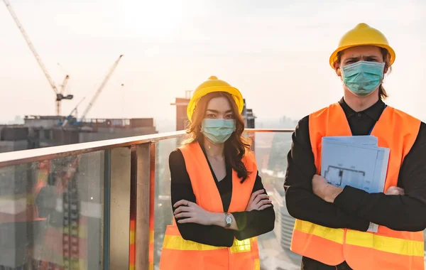 Engineers in mechanical factory reading instructions.smiling manufacture worker  man and woman stand confident with the background of white sky and building tower. Concept of industry building people with art flare background.
