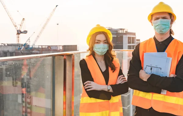 Engineers in mechanical factory reading instructions.smiling manufacture worker  man and woman stand confident with the background of white sky and building tower. Concept of industry building people with art flare background.