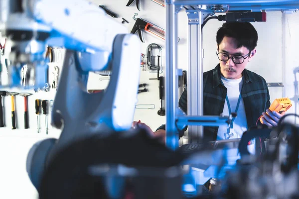 男性エンジニアメンテナンスロボットアーム研究室 彼は最新の機器を備えたハイテク研究所にいます テクノロジーとイノベーションの概念日本のプロの開発エンジニアは人工知能をテストしています ストック画像