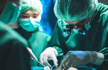 Cerrah doktor ameliyattan önce ameliyat eldiveni takıyor. Ameliyathanede doktor ve cerrahi venöz için asistan var..