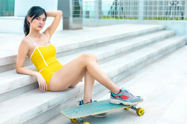 Asian young women surf skate or skates board outdoors on beautiful summer day. Happy young women happy play surf skate  at rooftop city bangkok.