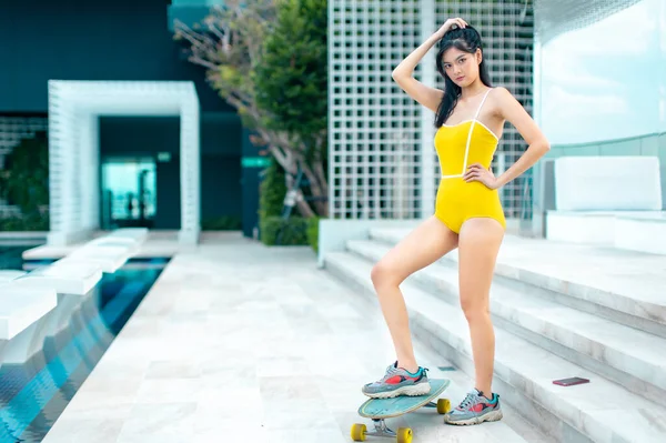 Asian young women surf skate or skates board outdoors on beautiful summer day. Happy young women happy play surf skate  at rooftop city bangkok.