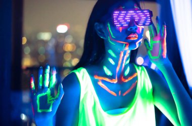 Neon Asyalı kadın dans ediyor. Neon ışıklı model kadın, floresan makyajlı güzel modelin portresi, UV 'de poz veren kadın disko dansçısının gelecek tasarımı, renkli makyaj..