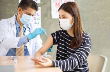 Genç hastaya kıdemli doktor şırıngası. Hastaneye maske takın. Sağlık sigortası konsepti..