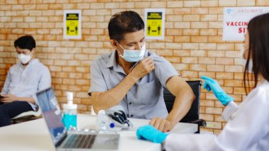 Coronavirus aşısı. Genç hastaya doktor enjeksiyonu. Hastanede maske takıldı. Covid-19 Aşısını Bekleme Odasında Bekleyen Hastalar..
