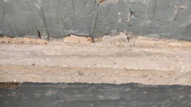 Close up of weathered wall with peeling paint and exposed wood showing signs of deterioration