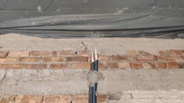 Exposed brick wall with cement repairs and a blue pipe running vertically through the center area