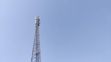 Sinyal iletim mobil ağ kulesi açık mavi gökyüzünün altında modern dijital teknolojiyi simgeliyor.