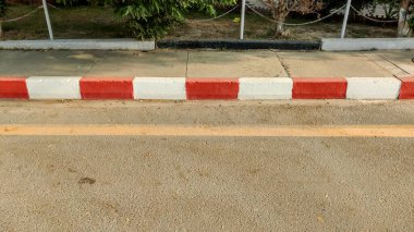 Asfalt yolu kaldırımdan ayıran kırmızı ve beyaz renkli kaldırım taşı