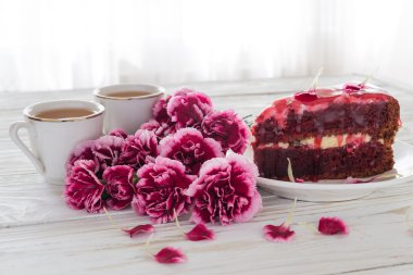 Kırmızı kadife kek, iki bardak çay ve pembe karanfil