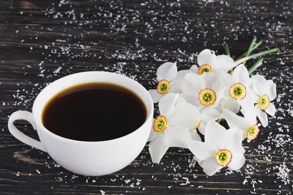 Tasse Kaffee und Narzisse auf schwarzem Holzhintergrund — Stockfoto