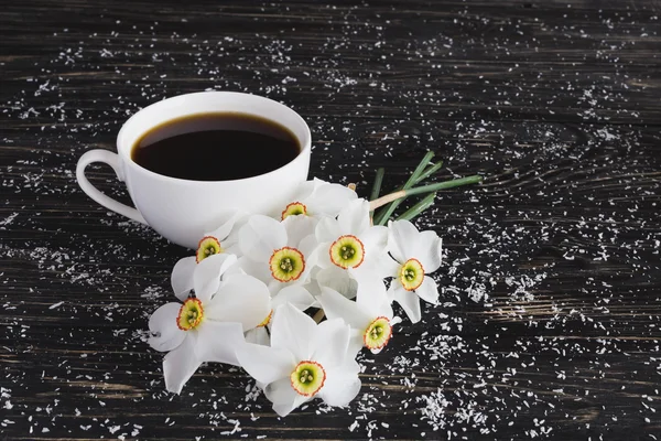 Tasse Kaffee und Narzisse auf schwarzem Holzhintergrund — Stockfoto