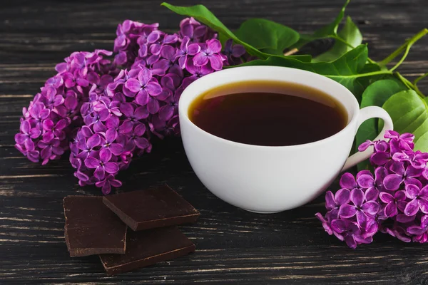 Tasse Kaffee, Schokolade und fliederfarbene Blumen — Stockfoto