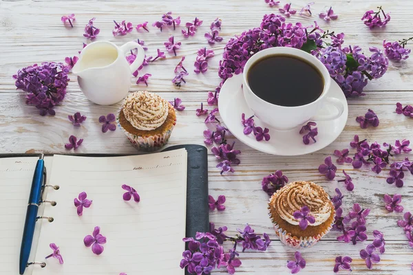 Cupcakes with cream, coffee, notebook and flowers