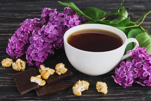 Tasse Kaffee, Schokolade und fliederfarbene Blumen — Stockfoto