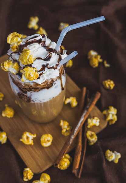 Glass of coffee with sour cream, caramel popcorn and chocolate