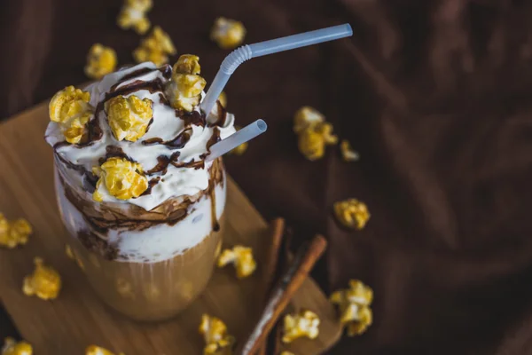 Glas kaffe med gräddfil, karamell popcorn och choklad — Stockfoto