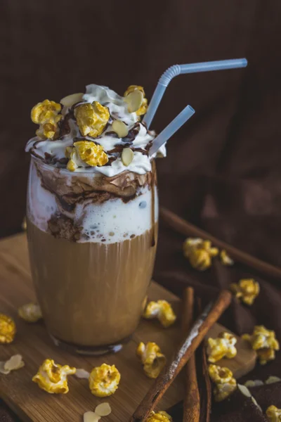 Glas kaffe med gräddfil, karamell popcorn och choklad — Stockfoto