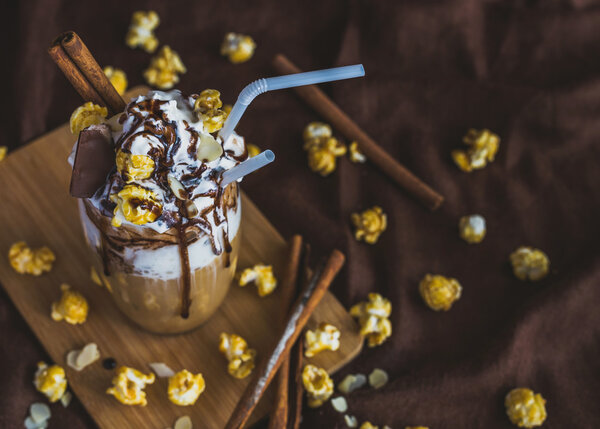 Glass of coffee with sour cream, caramel popcorn and chocolate