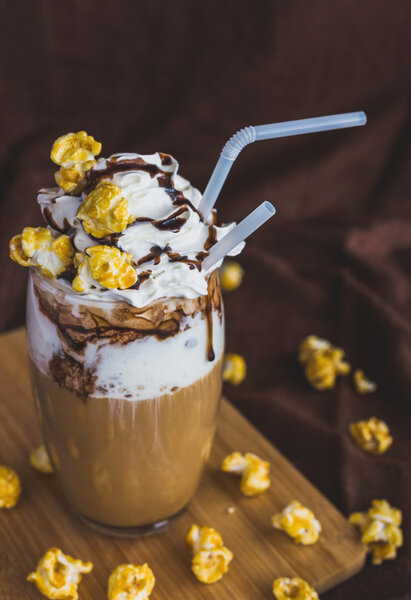 Glass of coffee with sour cream, caramel popcorn and chocolate