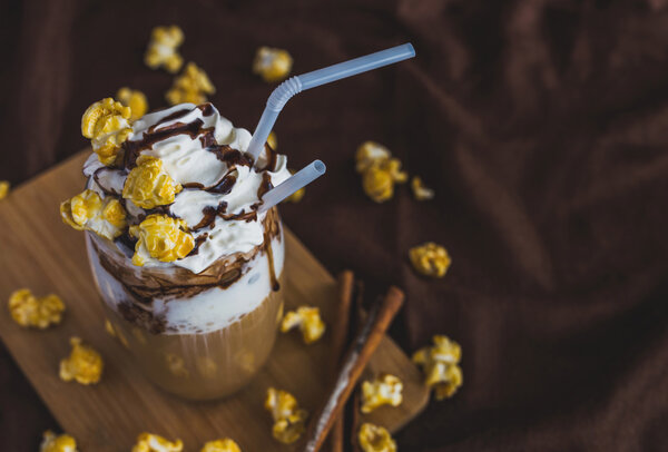 Glass of coffee with sour cream, caramel popcorn and chocolate