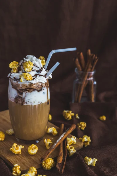 Glass of coffee with sour cream, caramel popcorn and chocolate — Stock Photo, Image