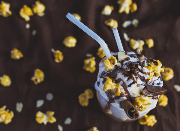 Glass of coffee with sour cream, caramel popcorn and chocolate