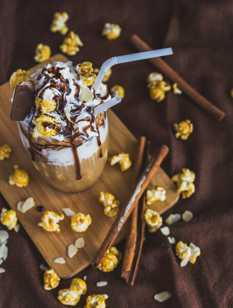 Glass of coffee with sour cream, caramel popcorn and chocolate