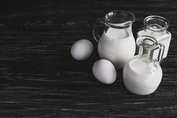 Milk jars and eggs on wooden background